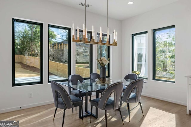 dining area featuring light wood-type flooring, an inviting chandelier, and plenty of natural light