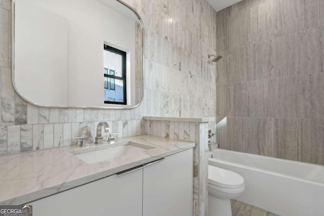 full bathroom featuring toilet, tiled shower / bath, backsplash, tile walls, and vanity