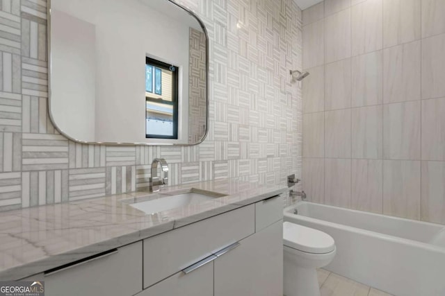 full bathroom featuring toilet, vanity, tile walls, backsplash, and tiled shower / bath