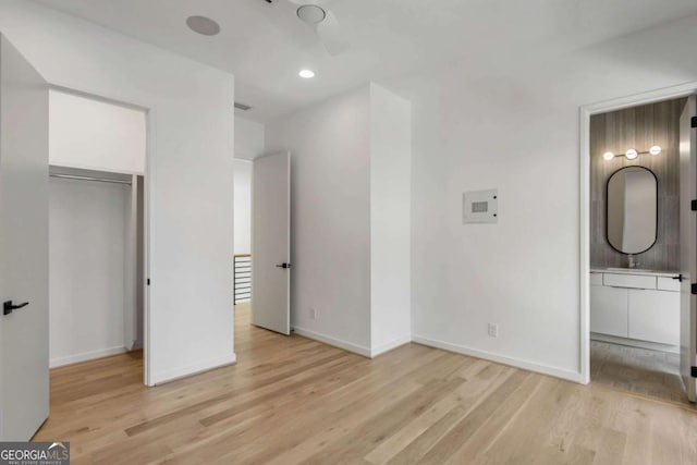 unfurnished bedroom with a closet, ensuite bathroom, and light hardwood / wood-style flooring