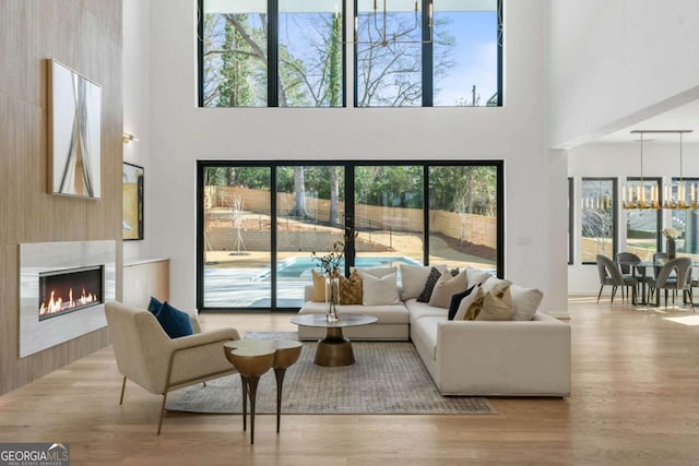 living room featuring a wealth of natural light, a fireplace, a high ceiling, and a notable chandelier