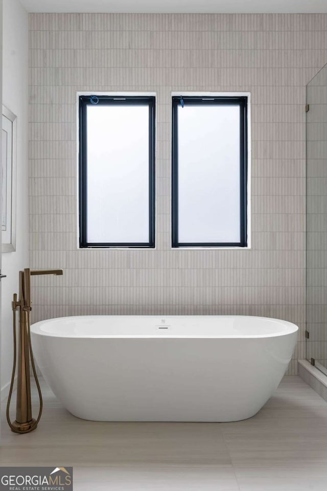 bathroom featuring tile walls, a bathtub, and tile patterned flooring