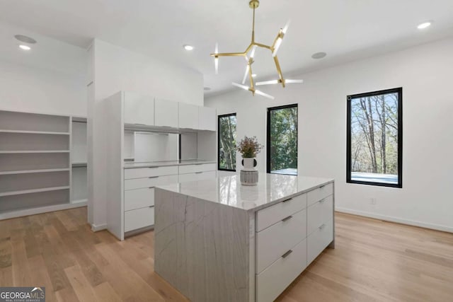 kitchen featuring white cabinetry, a notable chandelier, light wood-type flooring, hanging light fixtures, and a kitchen island