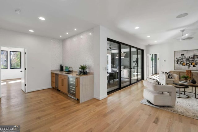 interior space featuring light wood-type flooring, ceiling fan, wine cooler, and sink