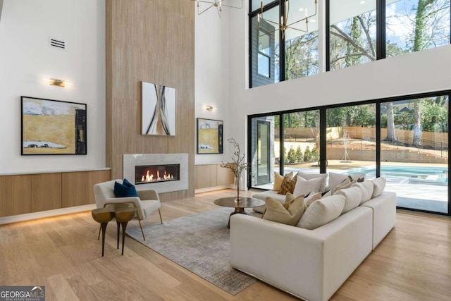 living room with an inviting chandelier, a high ceiling, and light hardwood / wood-style flooring