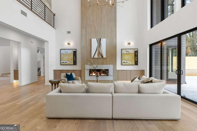 living room with wood-type flooring, a notable chandelier, and a high ceiling