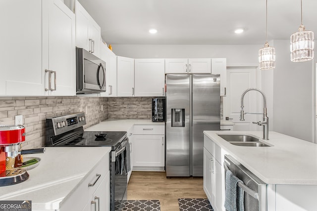 kitchen featuring sink, white cabinetry, appliances with stainless steel finishes, and pendant lighting