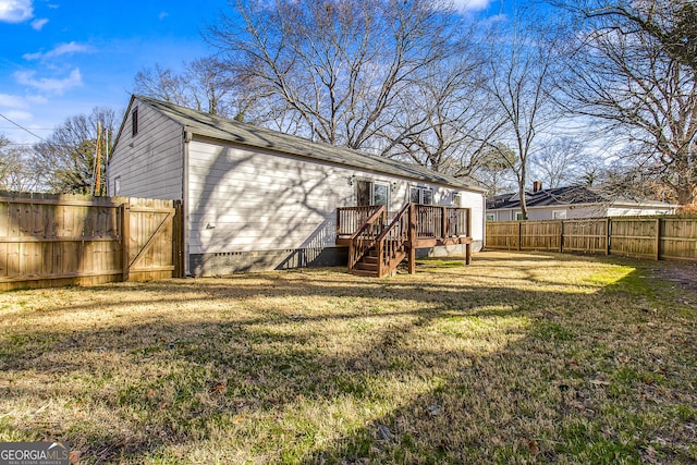 back of property featuring a wooden deck and a lawn