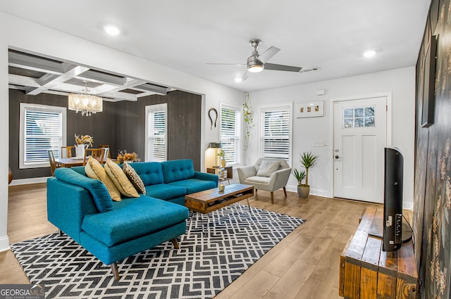 living room featuring ceiling fan with notable chandelier, light hardwood / wood-style flooring, beamed ceiling, and coffered ceiling