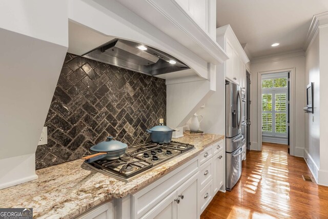 kitchen with wood-type flooring, sink, beamed ceiling, a tiled fireplace, and white cabinets