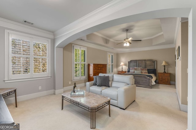 bedroom with ceiling fan, light colored carpet, a tray ceiling, and ornamental molding