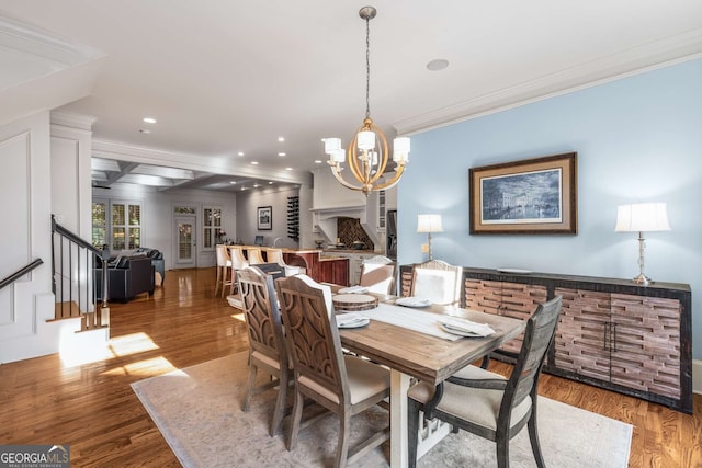 dining area with wood-type flooring, crown molding, and a chandelier