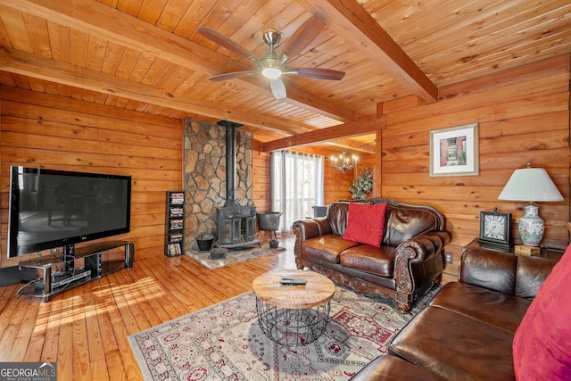 living room featuring wood ceiling, a wood stove, hardwood / wood-style flooring, and beamed ceiling