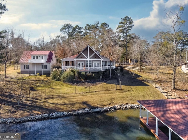 rear view of property with a water view and a lawn