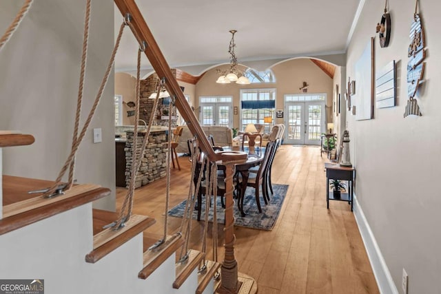 dining room with french doors, vaulted ceiling, a chandelier, crown molding, and light hardwood / wood-style flooring