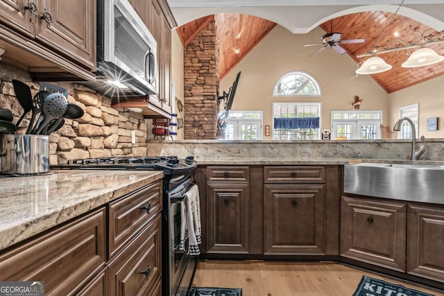 kitchen featuring appliances with stainless steel finishes, backsplash, vaulted ceiling, dark brown cabinetry, and sink