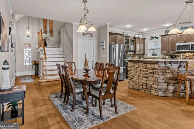 dining space with light hardwood / wood-style floors, ornamental molding, and a chandelier