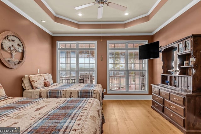 bedroom featuring ceiling fan, light hardwood / wood-style floors, ornamental molding, and a raised ceiling