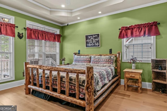 bedroom featuring a raised ceiling, crown molding, and hardwood / wood-style floors