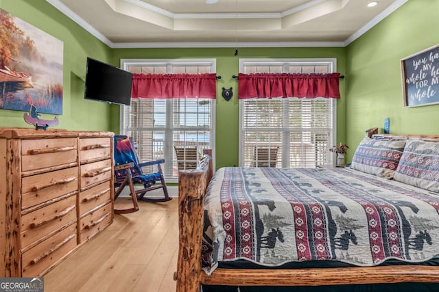 bedroom featuring a tray ceiling, ornamental molding, and light hardwood / wood-style floors