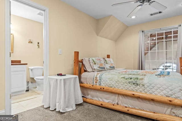 bedroom featuring ensuite bathroom, ceiling fan, light tile patterned flooring, and lofted ceiling