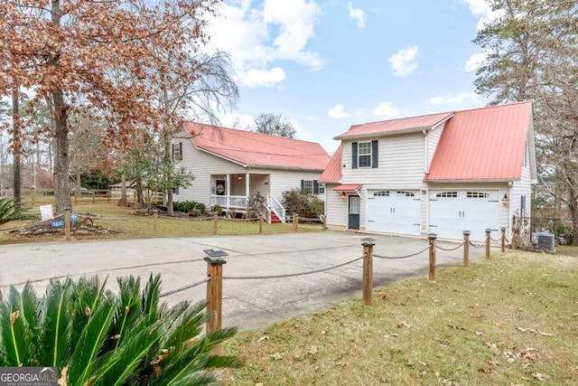 view of front property featuring a front lawn, a garage, cooling unit, and covered porch