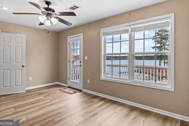 doorway to outside with ceiling fan, light hardwood / wood-style floors, and a water view