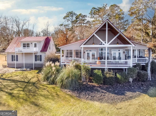 rear view of house featuring a wooden deck, french doors, and a yard