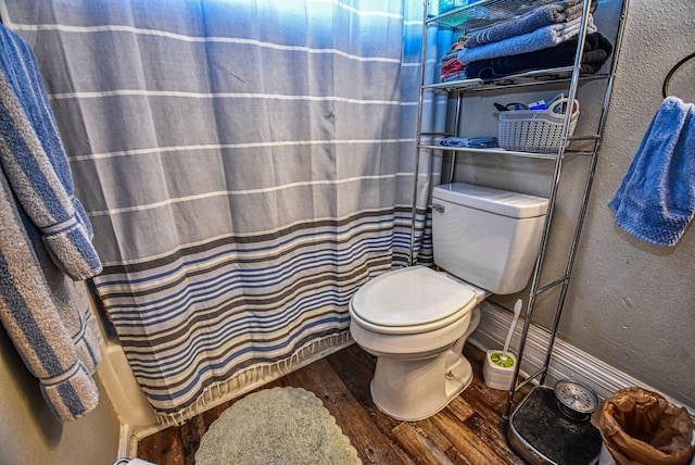 bathroom featuring toilet, wood-type flooring, and curtained shower