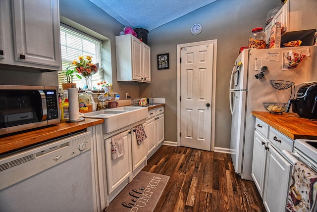 kitchen featuring white appliances, white cabinets, a textured ceiling, dark hardwood / wood-style floors, and butcher block countertops