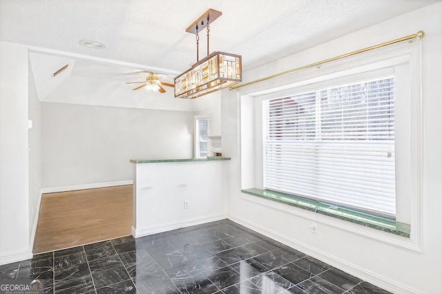 kitchen featuring pendant lighting, ceiling fan with notable chandelier, and a textured ceiling