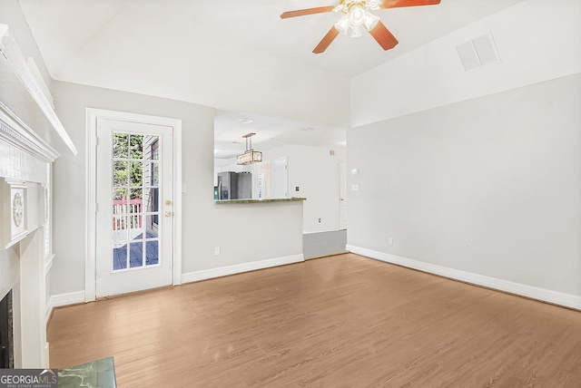 unfurnished living room featuring hardwood / wood-style flooring, vaulted ceiling, and ceiling fan