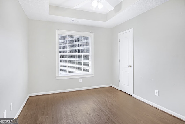 unfurnished room featuring wood-type flooring, ceiling fan, and a tray ceiling