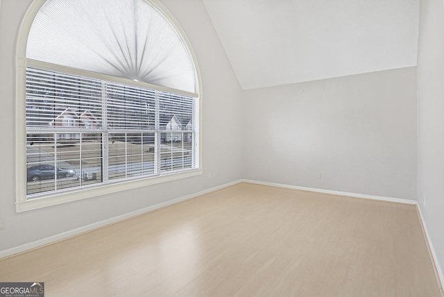 spare room featuring hardwood / wood-style flooring and vaulted ceiling