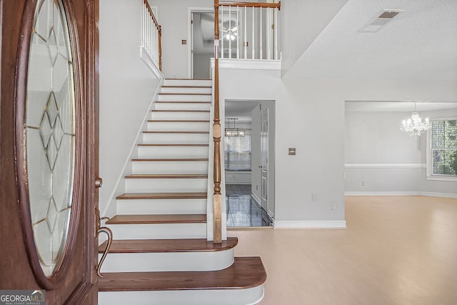 stairs featuring wood-type flooring, a towering ceiling, and a chandelier