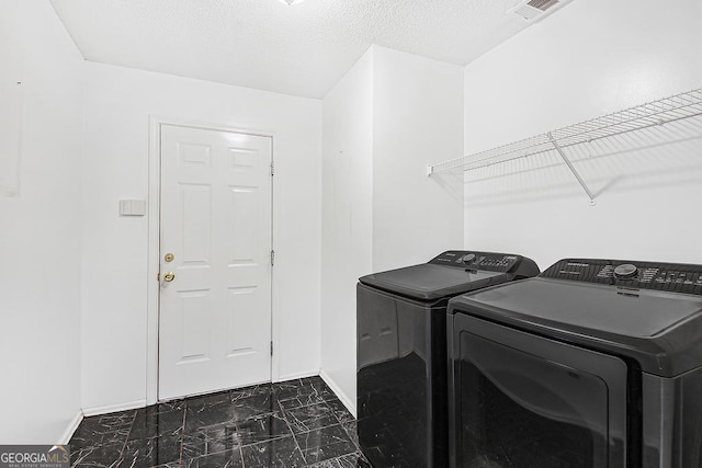 clothes washing area featuring washer and clothes dryer and a textured ceiling