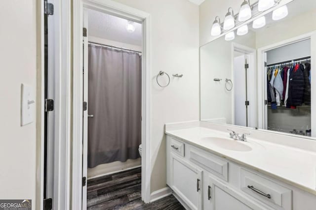 bathroom featuring toilet, hardwood / wood-style flooring, a textured ceiling, a shower with curtain, and vanity