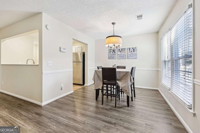 dining area with dark hardwood / wood-style flooring, a chandelier, and a textured ceiling