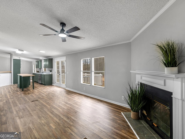 unfurnished living room with ceiling fan, dark hardwood / wood-style floors, a textured ceiling, crown molding, and a tile fireplace