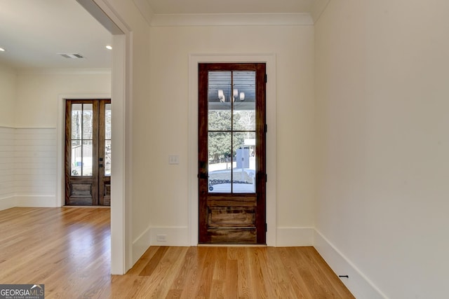 foyer entrance with light hardwood / wood-style floors and crown molding