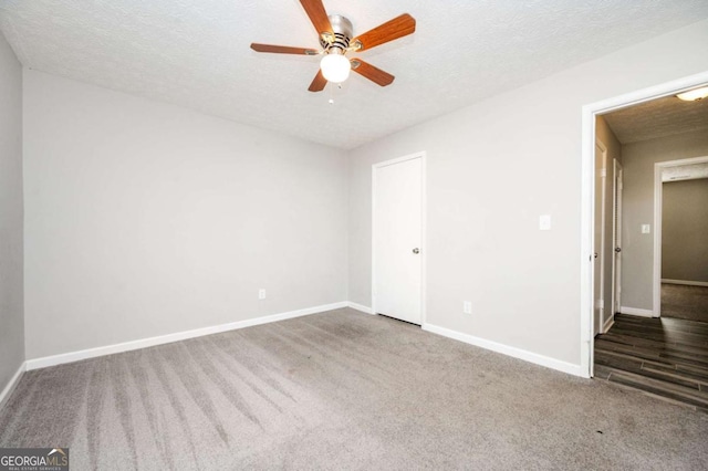 empty room with ceiling fan, dark carpet, and a textured ceiling