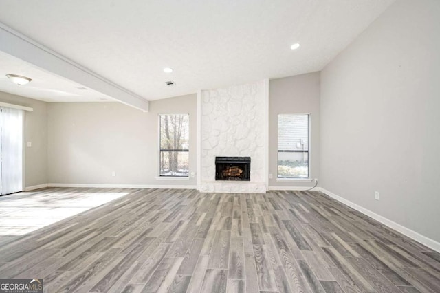 unfurnished living room with a fireplace, hardwood / wood-style flooring, and vaulted ceiling with beams