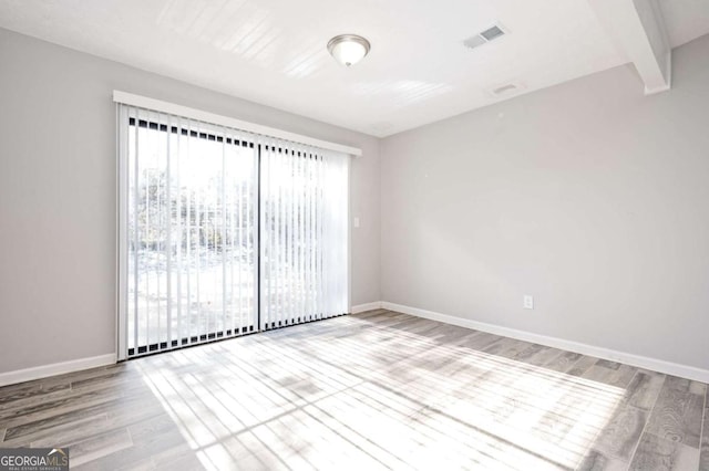 spare room featuring hardwood / wood-style flooring and beamed ceiling