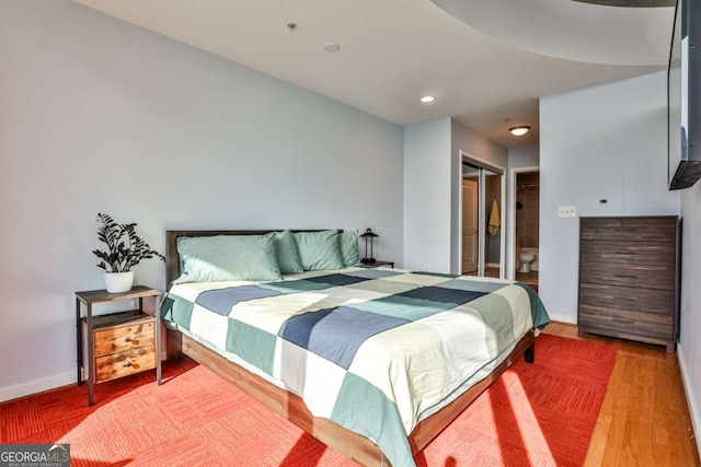 bedroom with a closet, hardwood / wood-style floors, and ensuite bath