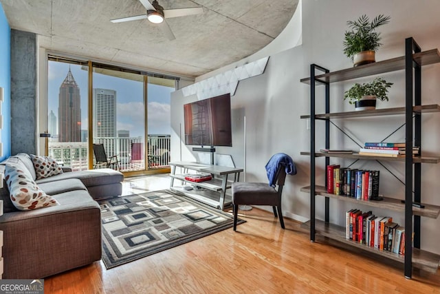 living room with ceiling fan, floor to ceiling windows, and light hardwood / wood-style flooring