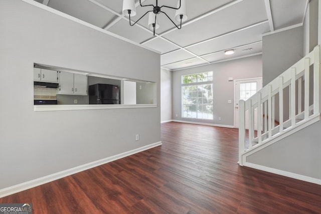 unfurnished living room featuring an inviting chandelier and dark hardwood / wood-style flooring