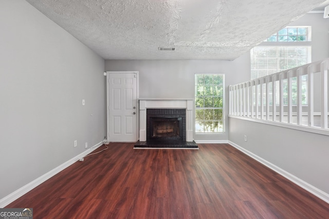 unfurnished living room with a textured ceiling, dark hardwood / wood-style floors, and a fireplace