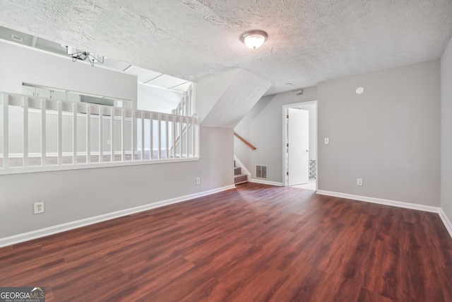 additional living space with dark wood-type flooring and a textured ceiling