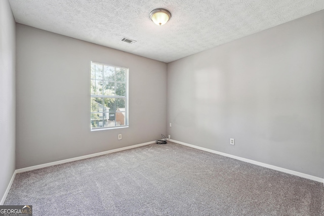 empty room with a textured ceiling and carpet flooring