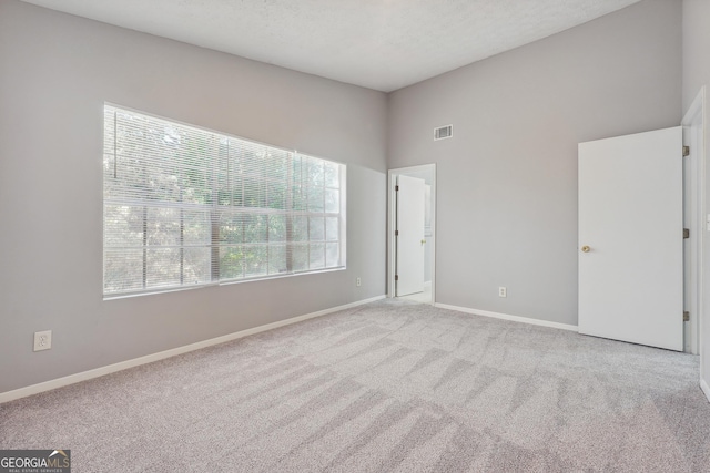 carpeted empty room with a textured ceiling